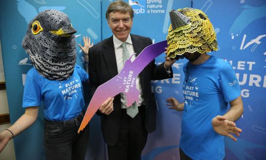 Philip Dunne MP holding a curlew cut-out, flanked by RSPB volunteers dressed as a cuckoo and a yellowhammer.